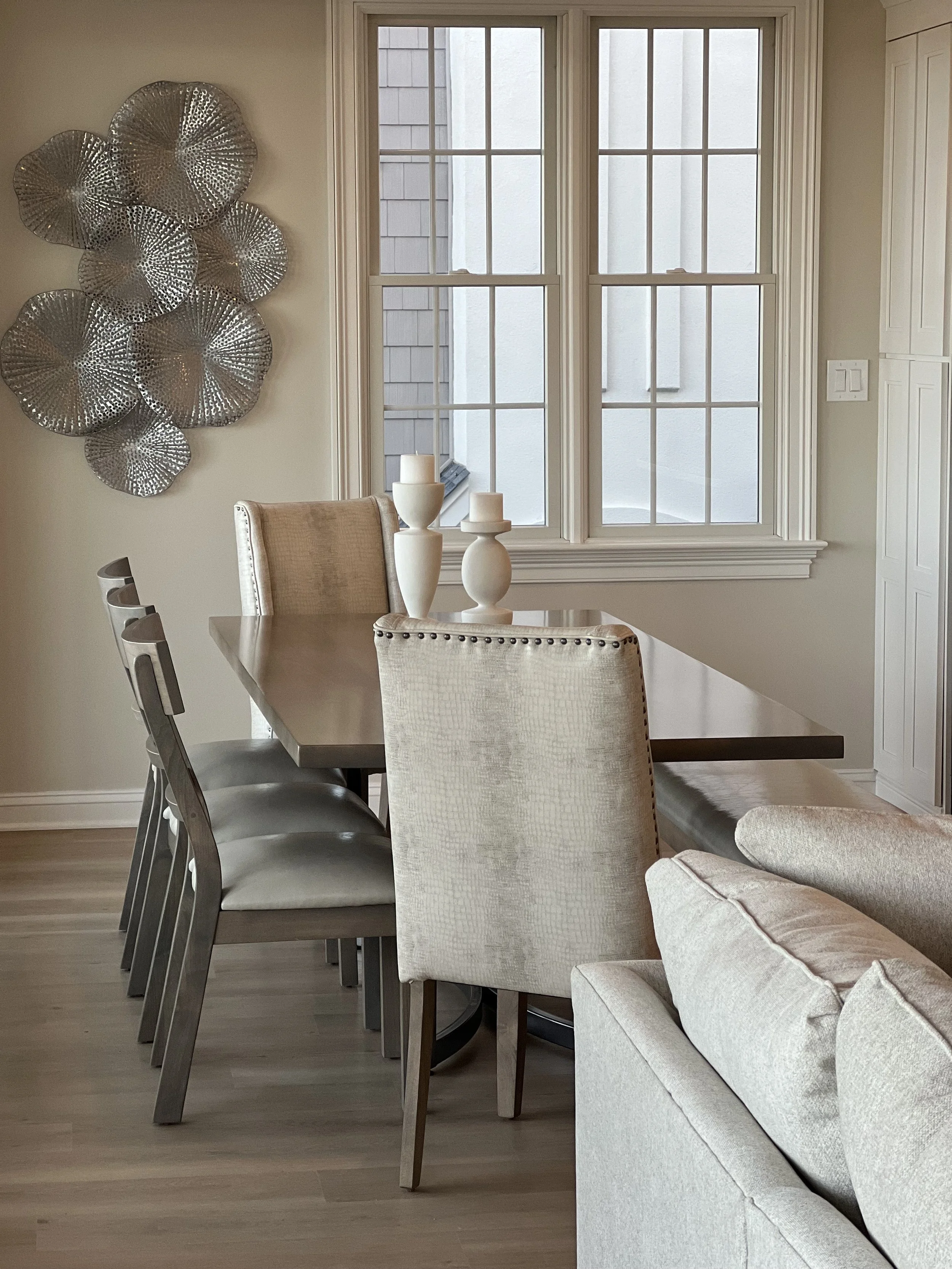 Neutral dining room with wood table, upholstered chairs and modern wall decor