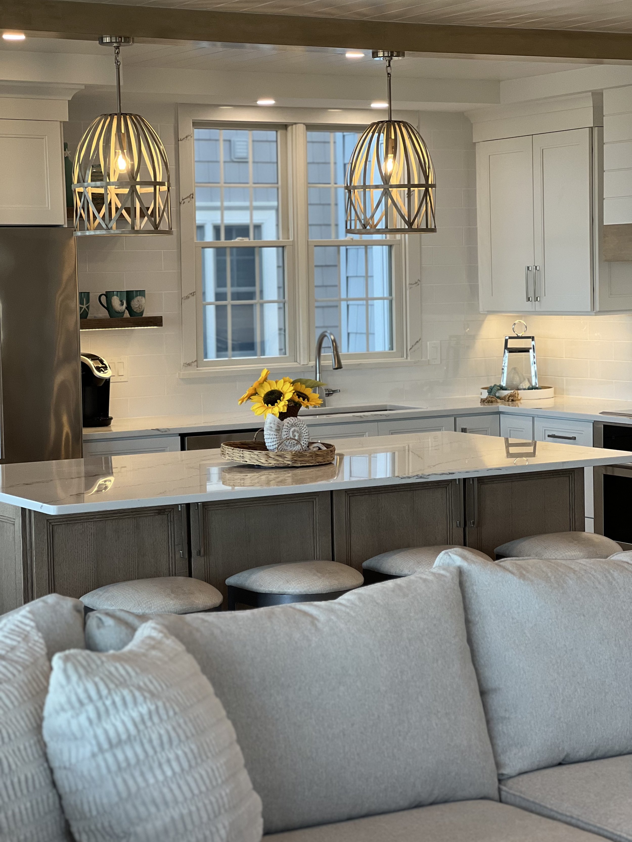 Bright kitchen with white cabinetry, pendant lighting, sunflowers and neutral furnishings