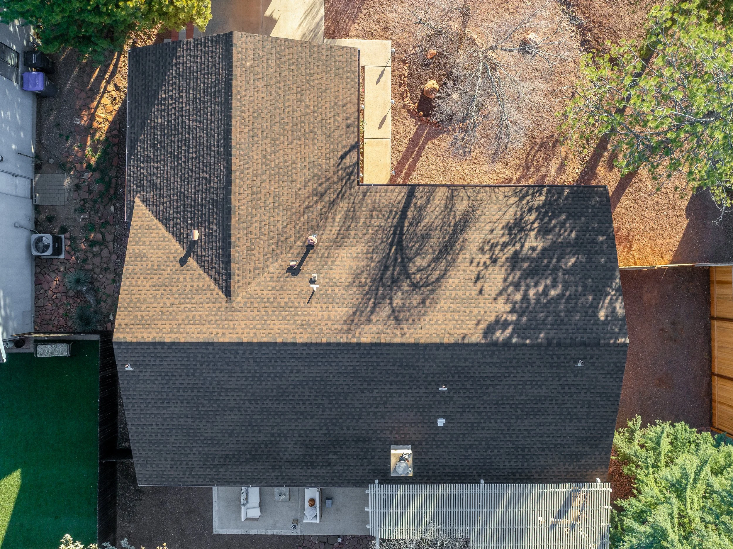 An aerial view of a house roof with dark shingles.