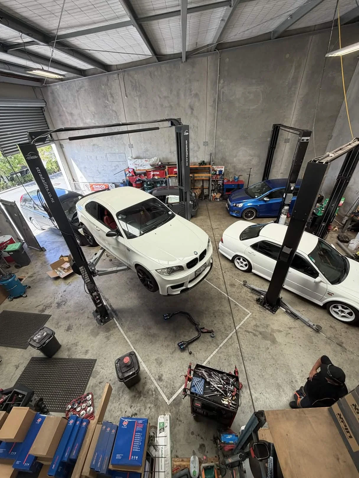 An automotive workshop with three cars on car lifts, tools, and workshop equipment.