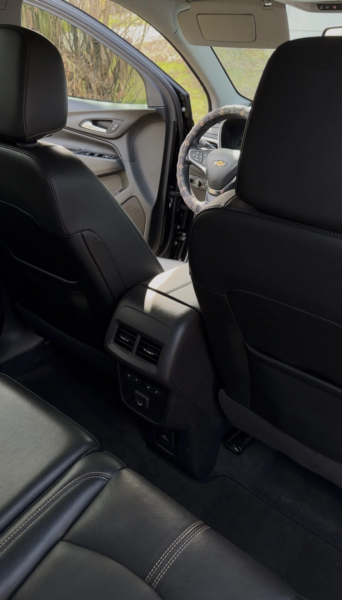 Interior of a Chevrolet vehicle showing black leather seats, rear air vents, and the steering wheel with Chevrolet logo.