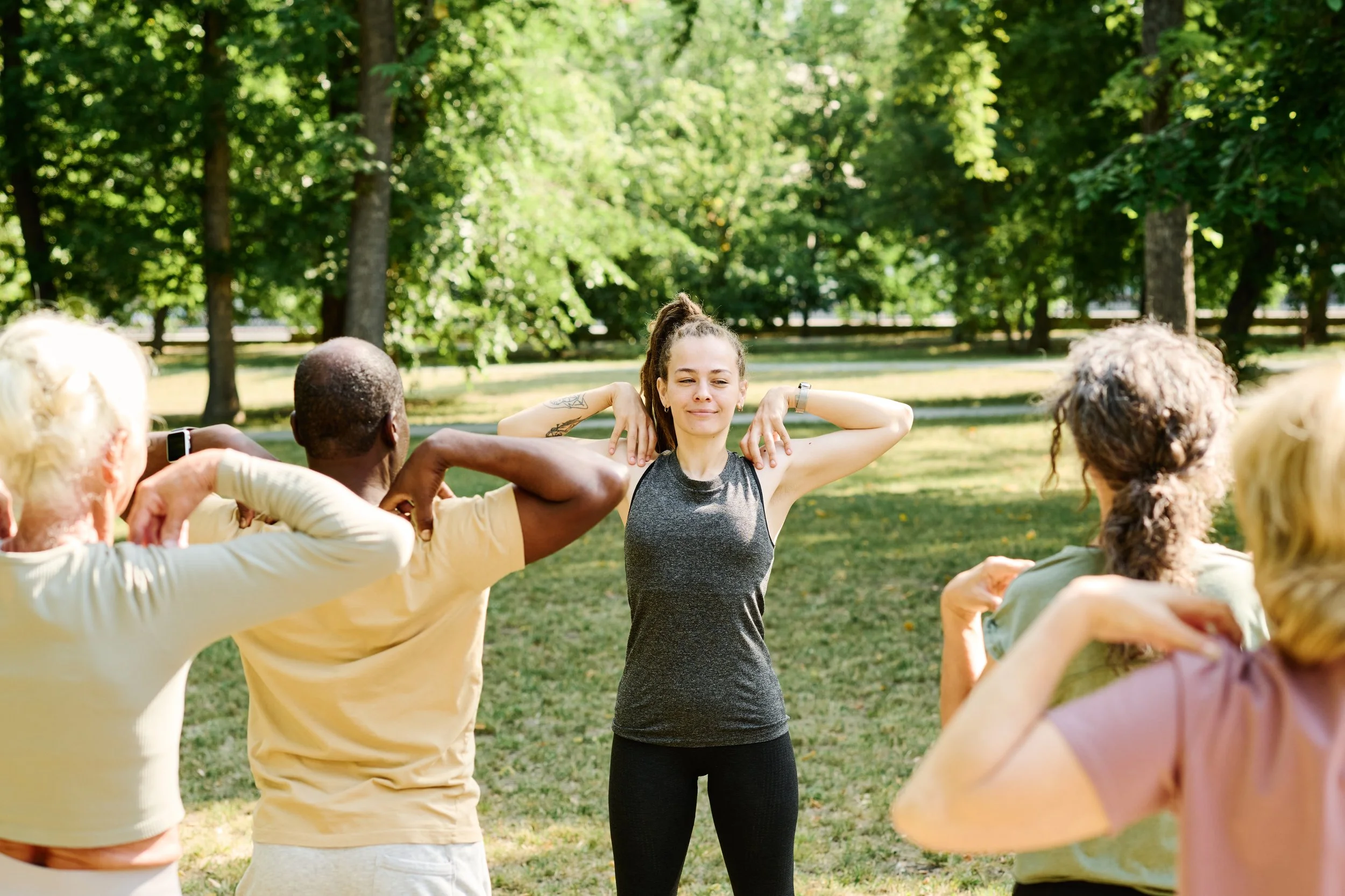 People practicing mindful stretching and healthy routines together outdoors in a sunlit park, representing subconscious behavior changes and habit control.