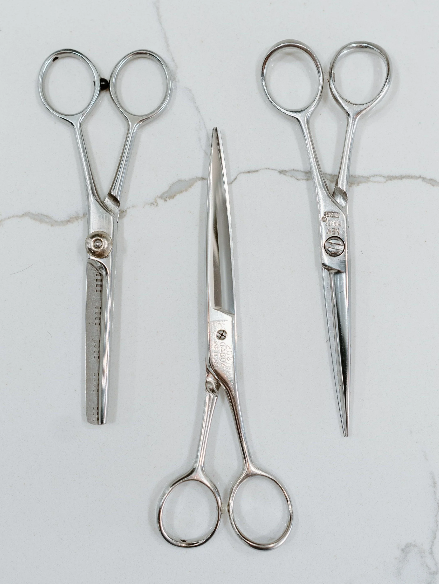 Three pairs of surgical scissors placed on a white surface.