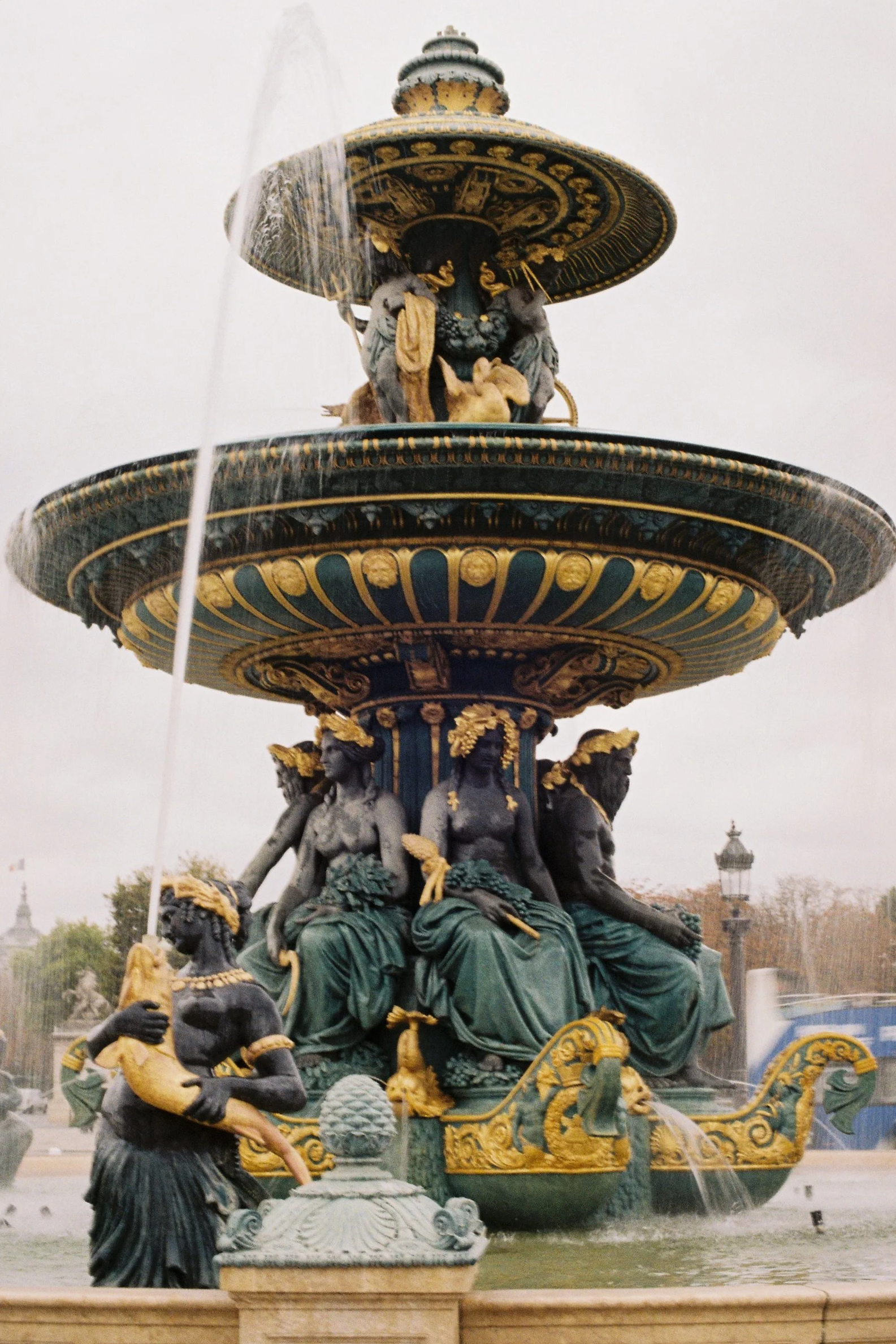 A decorative fountain with multiple statues and ornate design, featuring water streams and sculptures of human figures and animals, situated outdoors.