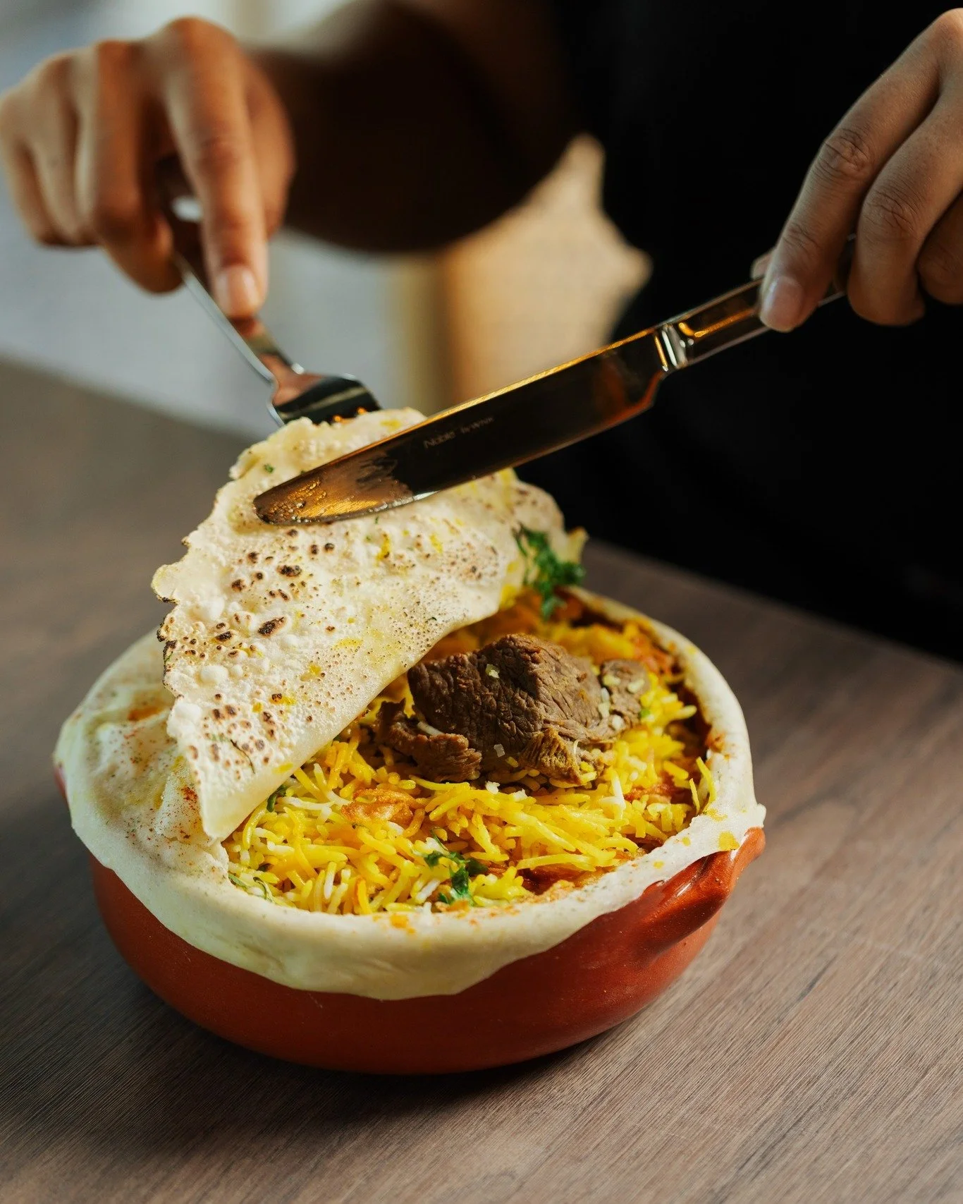 They say the best biryanis are sealed with patience. 😌

Ours arrives tucked beneath a blistered crust, baked slow in a clay pot until the saffron rice turns fragrant, the lamb falls apart, and the whole table goes silent for a moment.

Break the sea