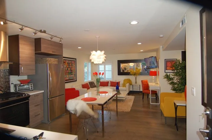 Open-concept living space with a kitchen and dining area featuring colorful furniture, modern decor, and a flat-screen TV.