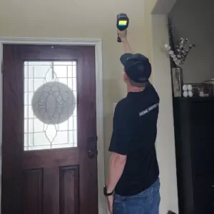 Home inspector Daniel using a thermal camera to scan interior walls for hidden moisture and heat loss during a home inspection in Spring, Texas.