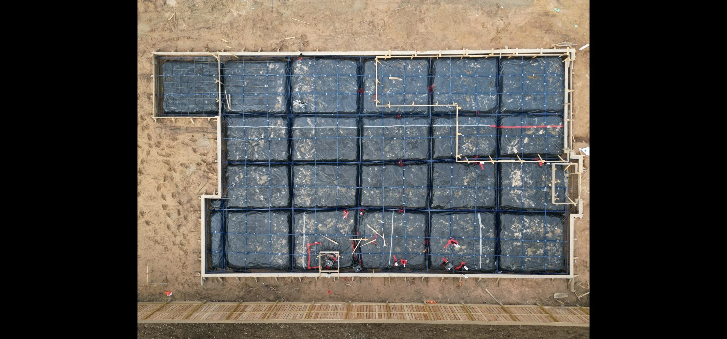 Drone photo of a post-tension concrete foundation slab during a pre-pour inspection, showing tendons and plumbing layout.
