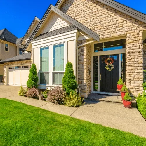 Exterior of a typical Spring, Texas suburban brick home with a manicured lawn and driveway on a sunny day.