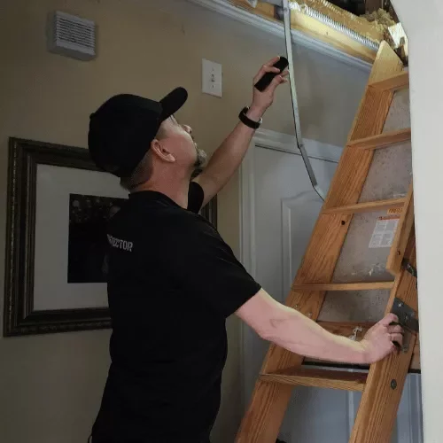 Home inspector Daniel inspecting an attic with a flashlight during a detailed home inspection in Spring, Texas.