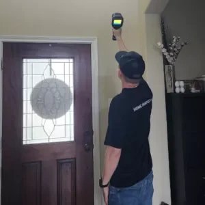Home inspector Daniel using a thermal camera to scan interior walls for hidden moisture and heat loss during a home inspection in Spring, Texas.