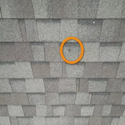 Close-up of an asphalt shingle roof showing light hail damage with small impact marks and minor granule loss.
