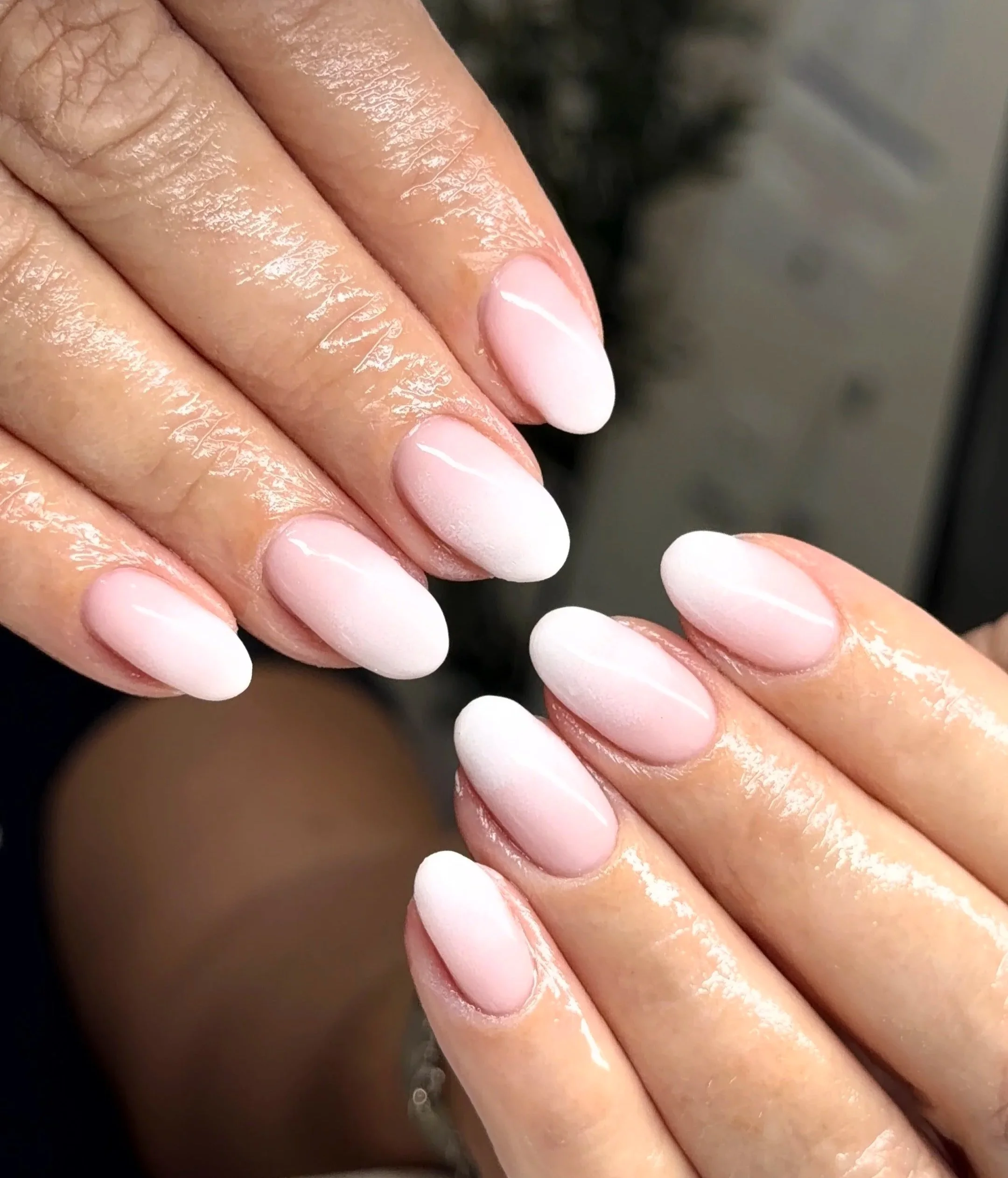 Close-up of manicured hands with light pink, gel, almond-shaped nails.
