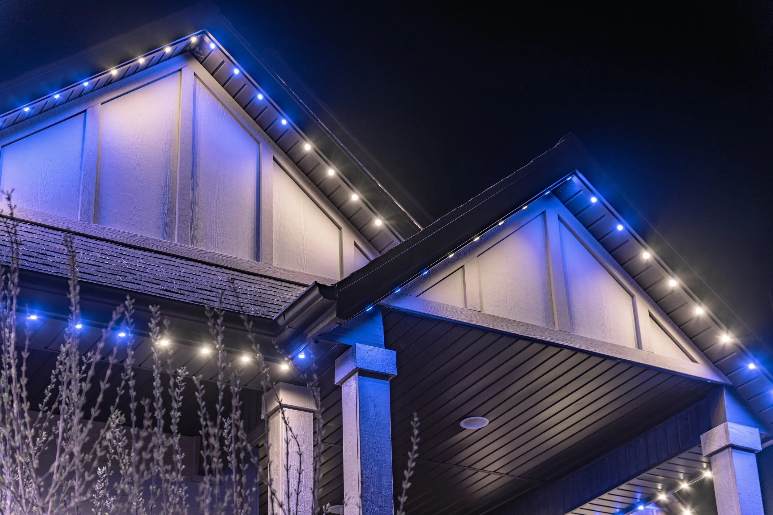 Blue and white permanent roofline lighting installed on a Utah home for year-round exterior lighting.