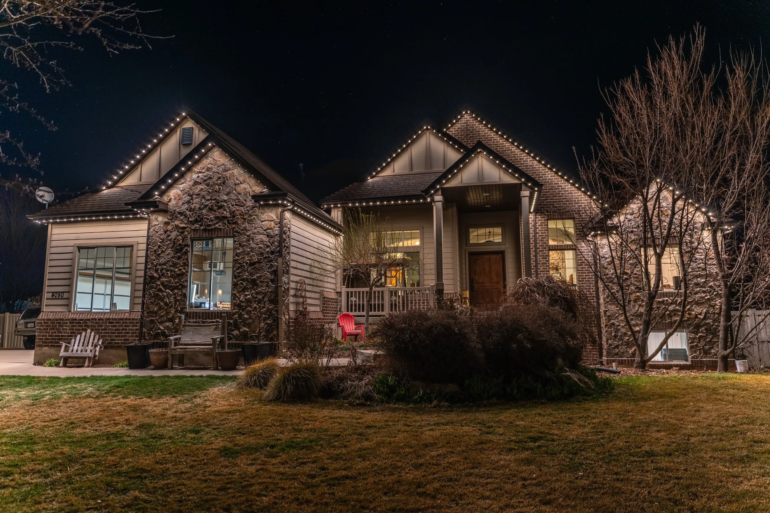 Residential home in Northern Utah featuring permanent LED roofline lighting at night with warm white tones.