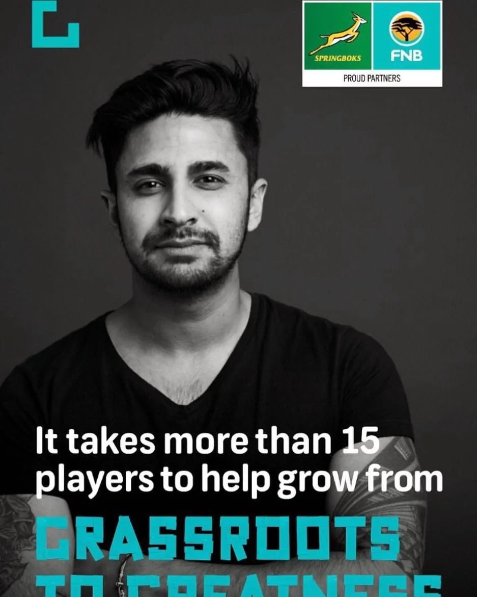 Black and white photo of a young man with dark hair and a beard, wearing a black shirt, with text about growing from grassroots to greatness. logos of Springboks and FNB in the top right corner.
