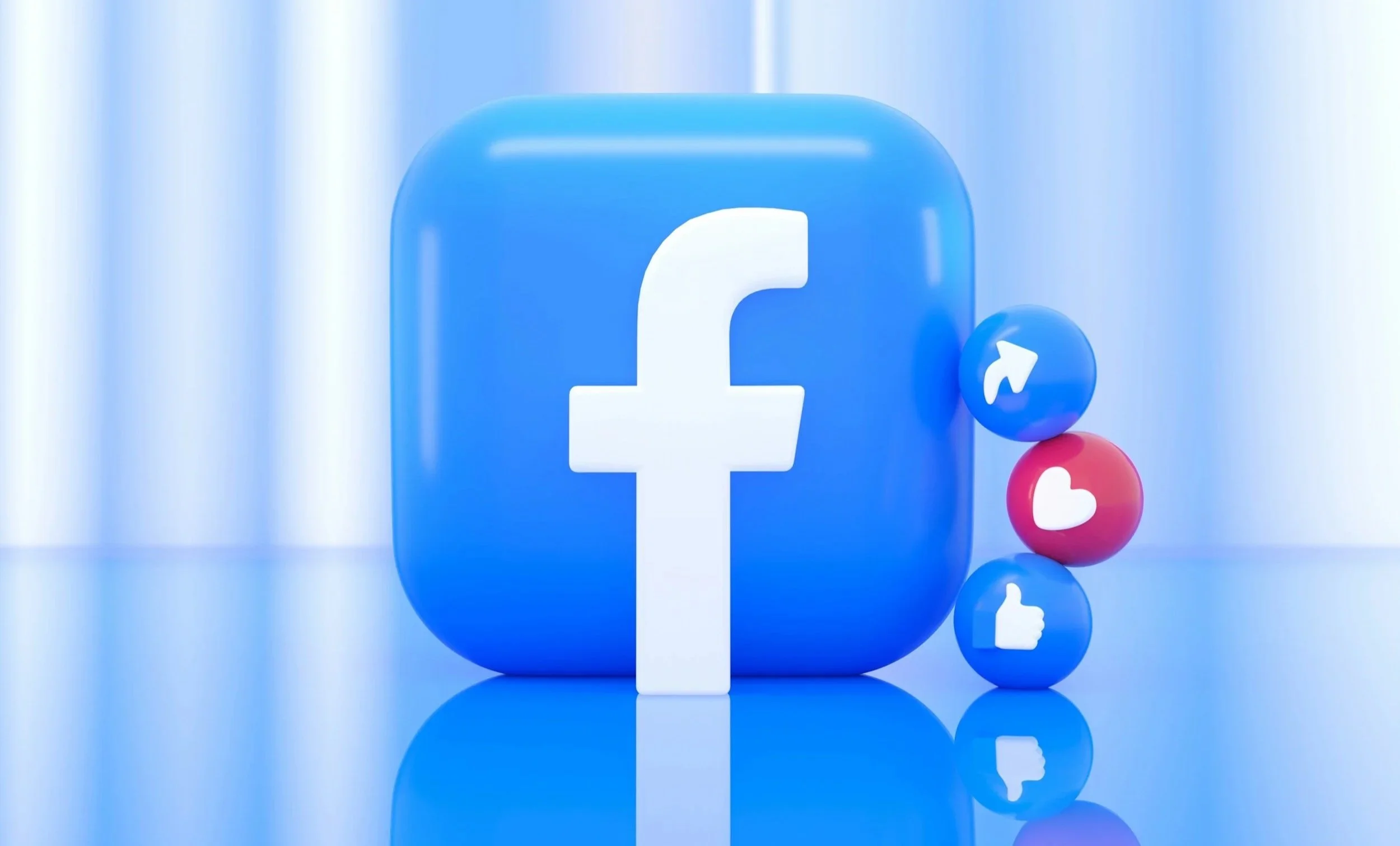 A 3D blue square with rounded edges featuring the white Facebook logo. To the right, four circular icons are stacked vertically: a blue share arrow, a red heart, a blue thumbs up, and a small portion of each reflecting on the glossy surface.