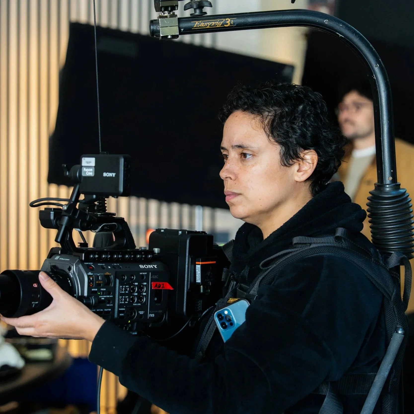 Cinematographer operating a Sony FX9 camera on a body-mounted EasyRig system during a film production.