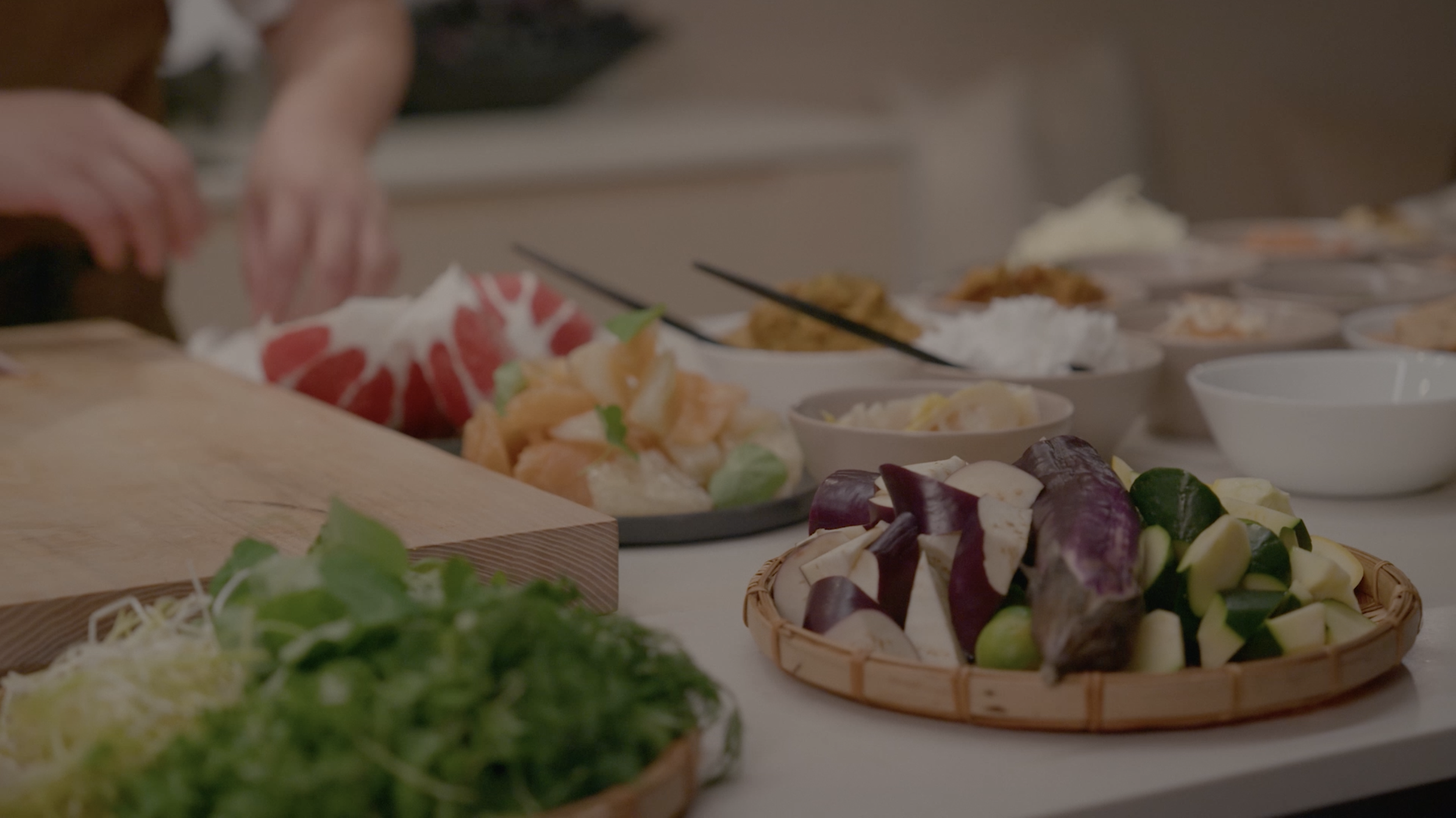 Table covered with assorted Asian dishes, vegetables, dumplings, and dipping bowls during a shared meal