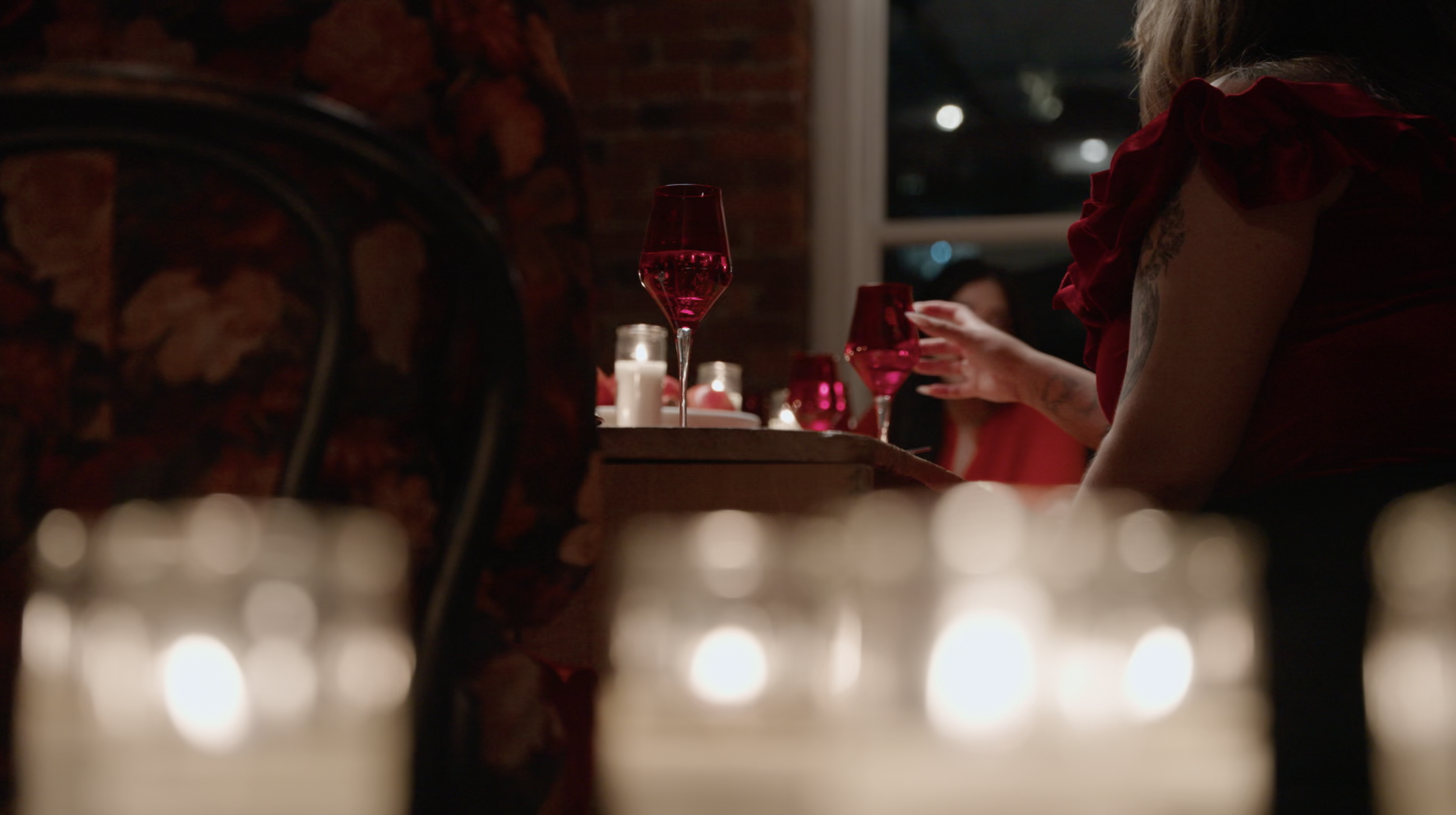 Romantic candlelit dinner with red wine glasses and guests in red attire