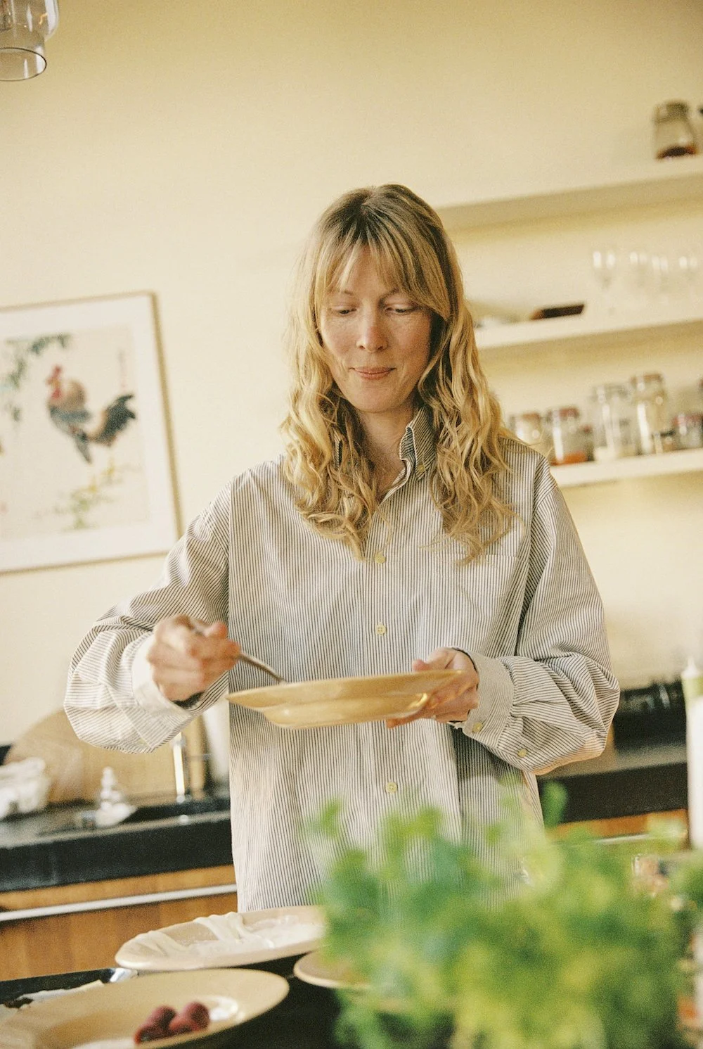 Merel Nolet, oprichter van het Oogstatelier die in een keuken een bord vasthoudt.