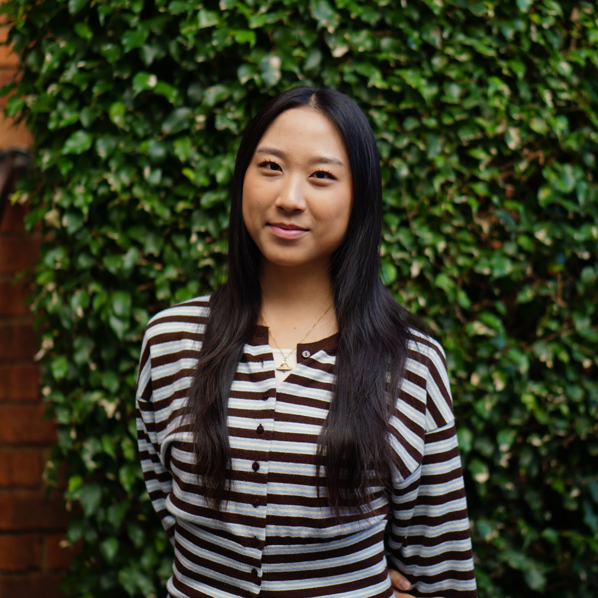Headshot of smiling female tutor with long braids wearing a lanyard.