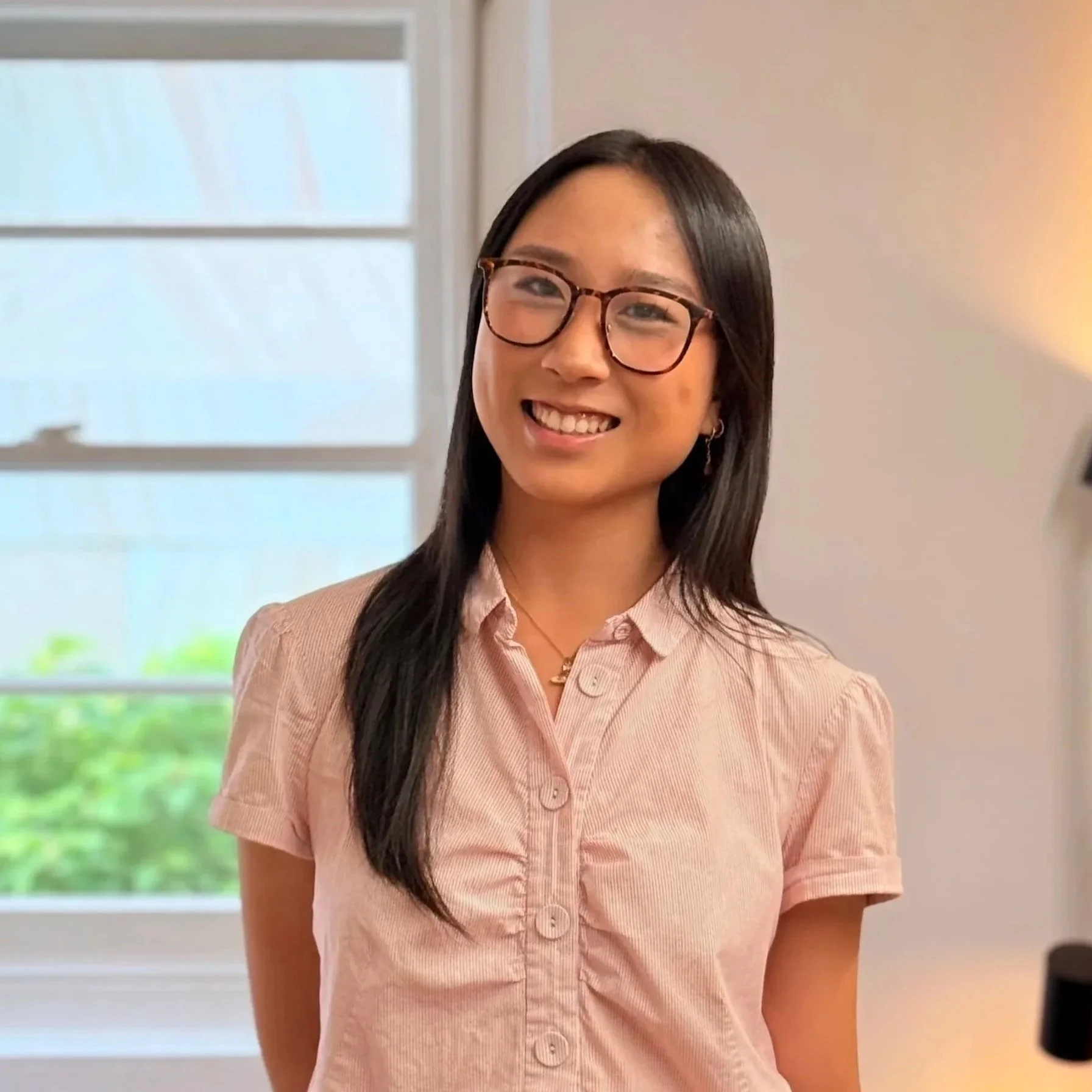 Headshot of smiling female tutor with long braids wearing a lanyard.