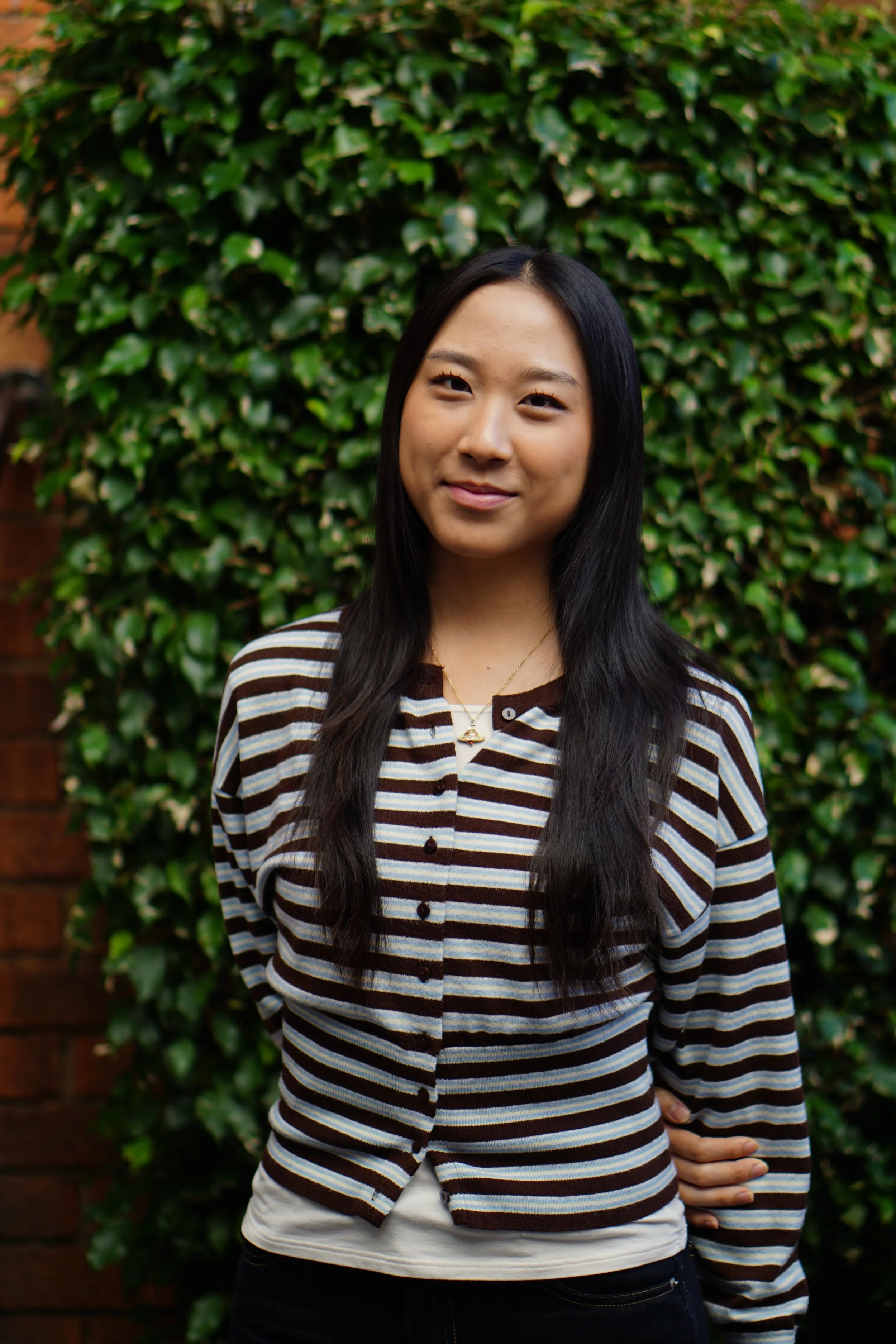 Headshot of smiling female tutor with long braids wearing a lanyard.