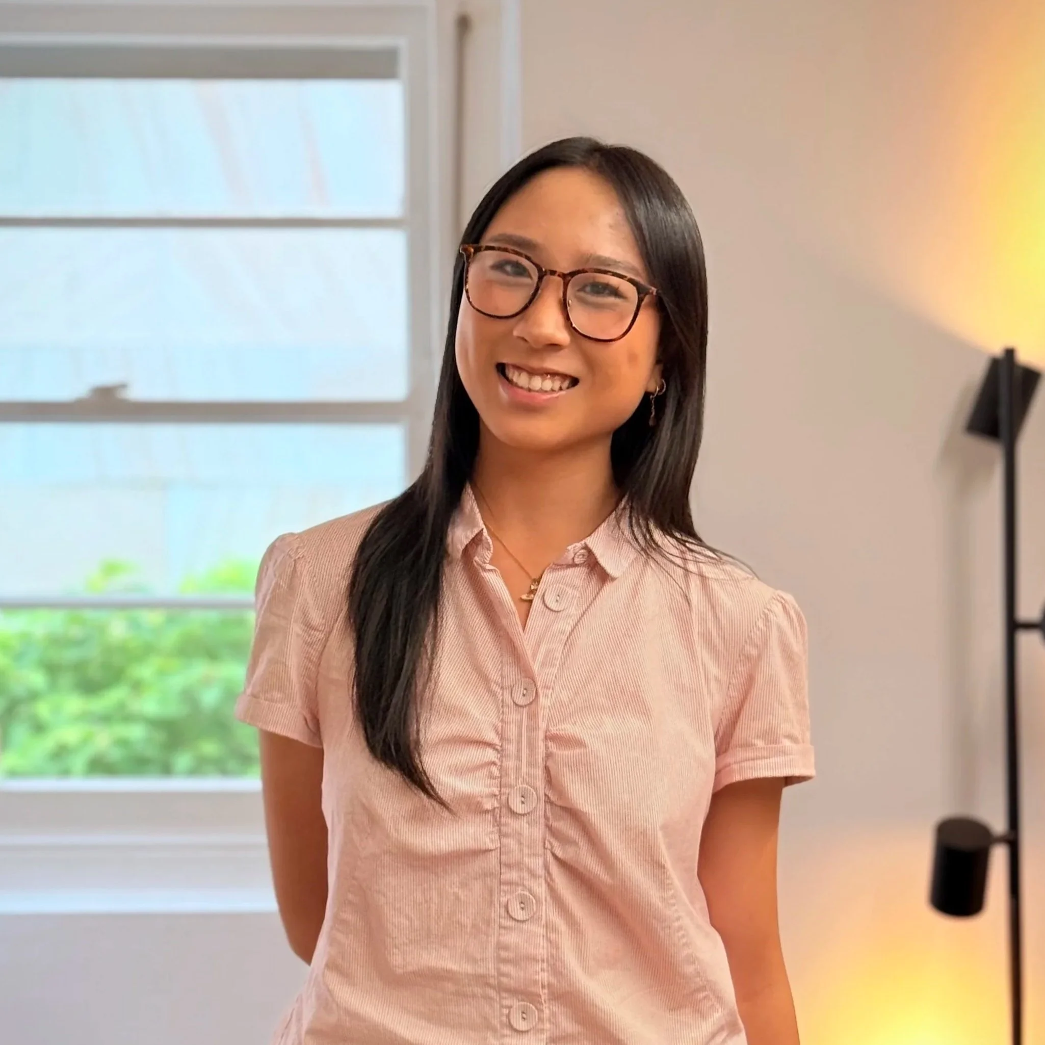 Headshot of smiling female tutor with long braids wearing a lanyard.