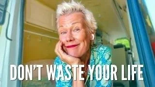 An elderly woman with white hair smiling and resting her chin on her hand inside a colorful bus, with text saying 'DON'T WASTE YOUR LIFE'.