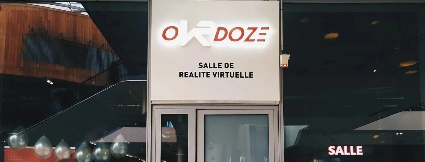Sign on a building advertising a virtual reality room, with the text 'OXR DOZE' and 'SALLE DE REALITE VIRTUELLE'.