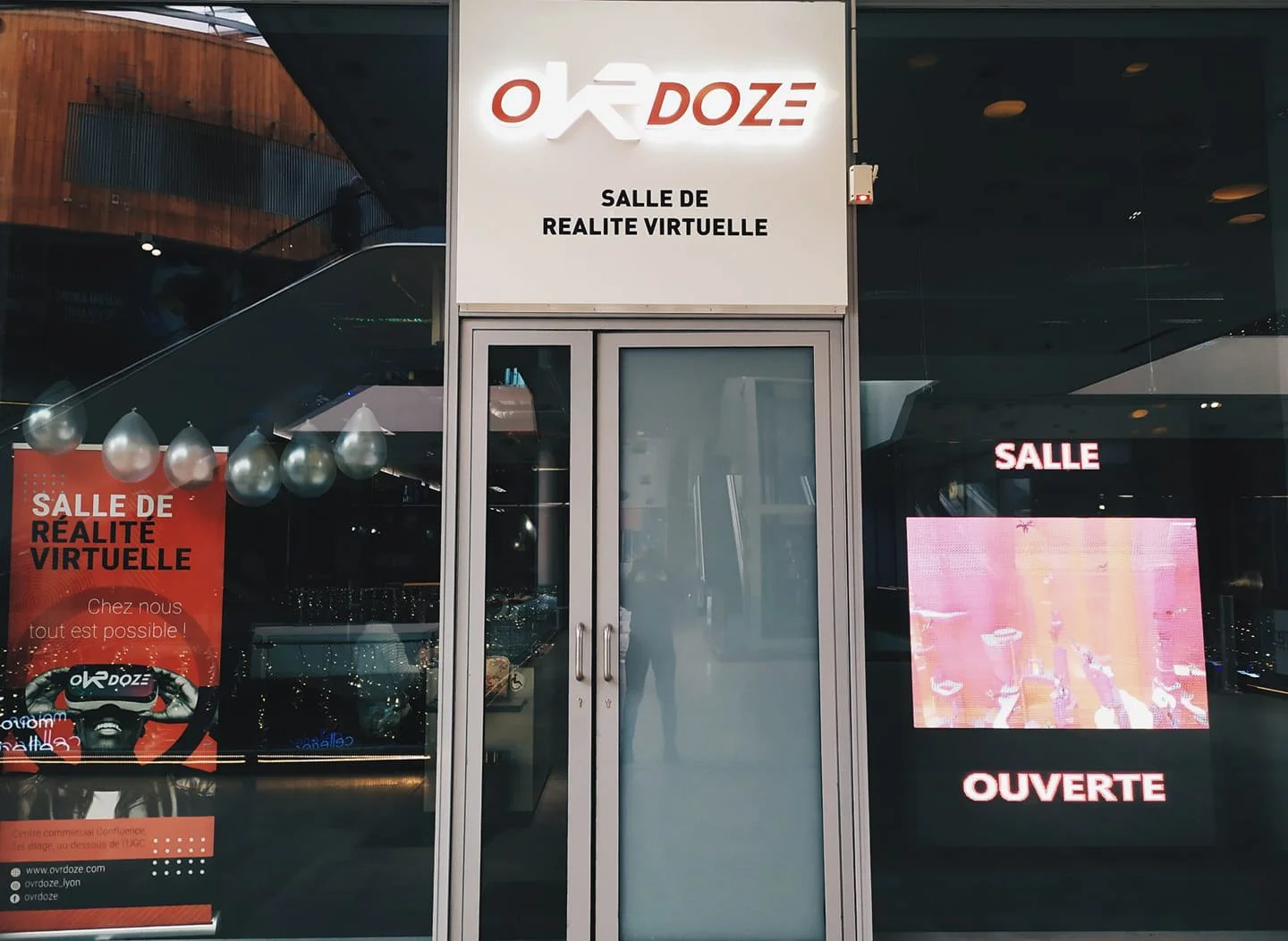 The entrance of a virtual reality room called 'Où Doze' with signs in French indicating it is open and a promotional poster inside.
