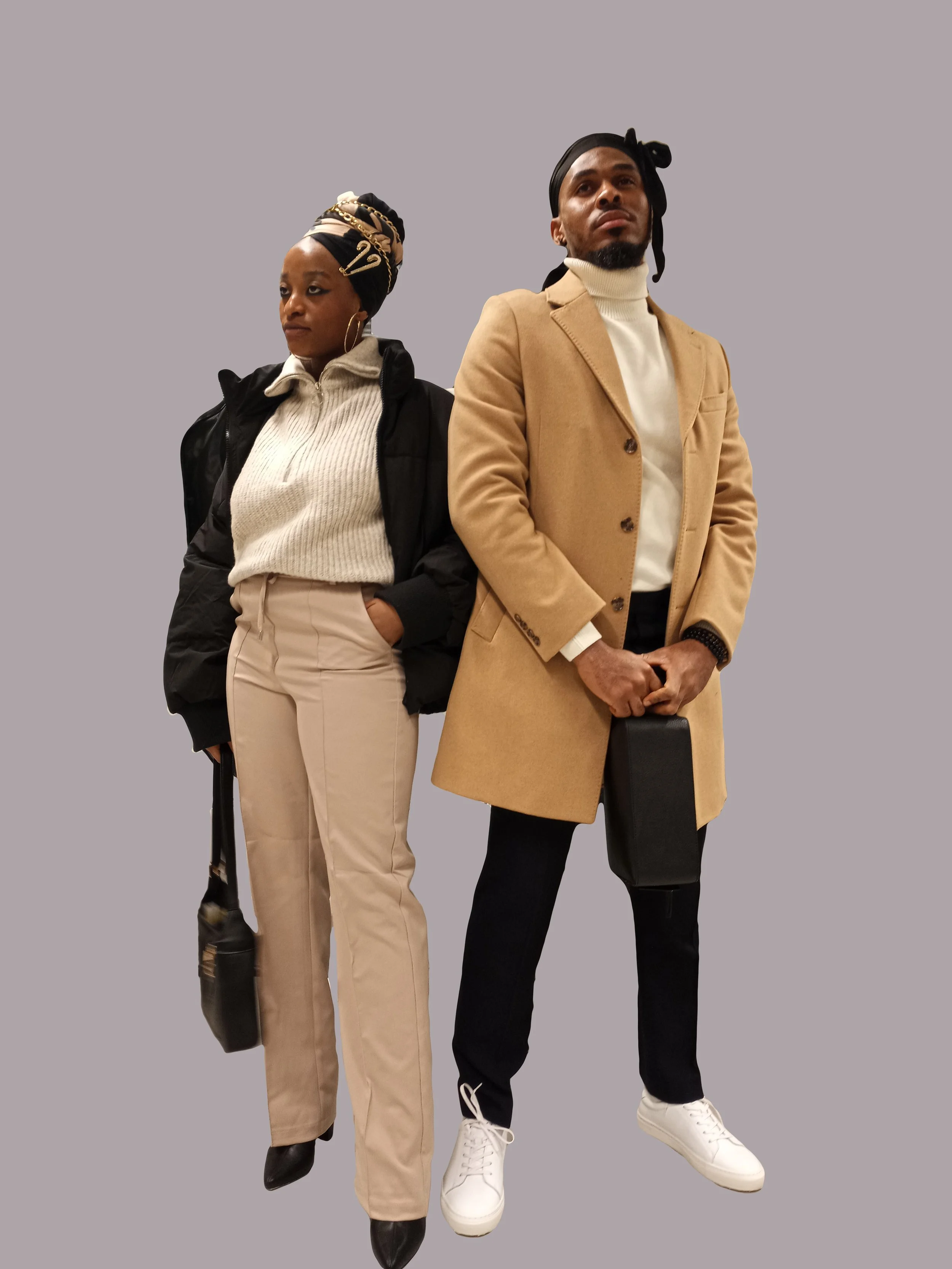 A man and woman standing side by side against a gray background. The woman is wearing a beige turtleneck sweater, beige pants, black boots, hoop earrings, and a headwrap with gold accents. The man is wearing a beige coat over a white turtleneck, black pants, white sneakers, and a black headscarf.
