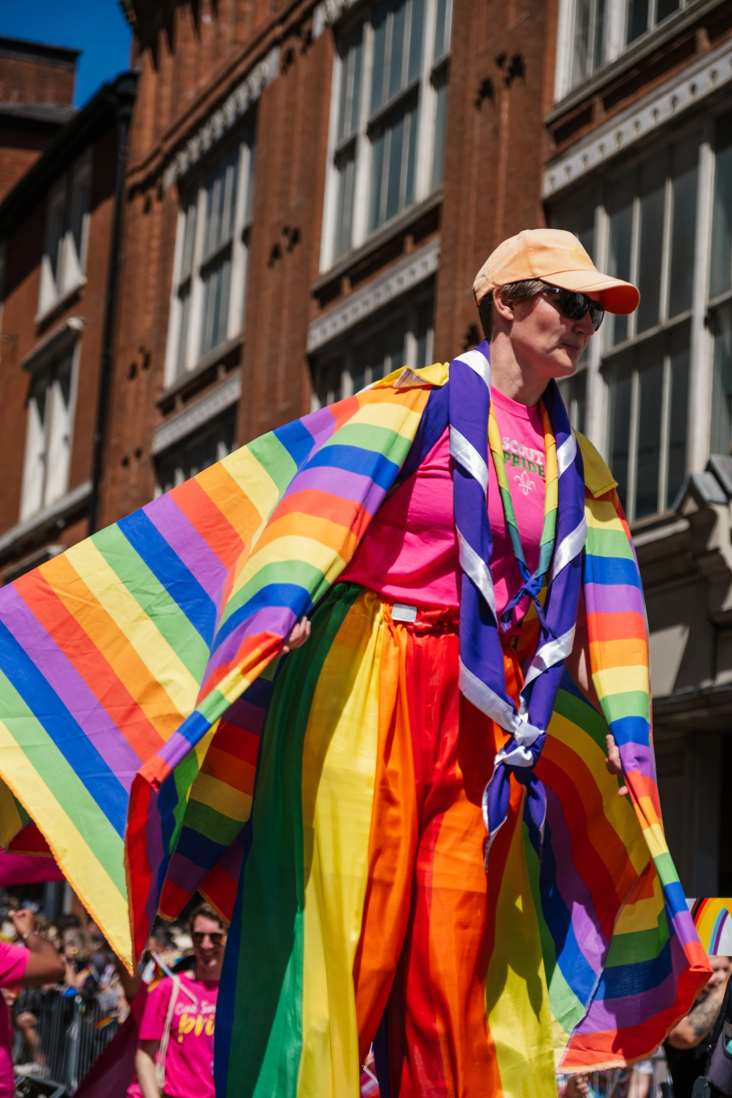 A person dressed in rainbow Pride flag clothing and accessories participating in a Pride parade.