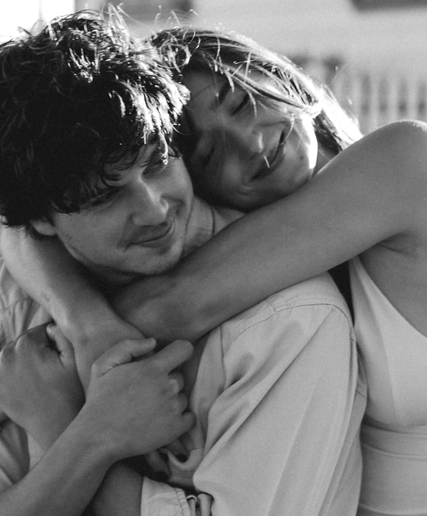 Two people hugging each other, smiling, with their eyes closed, in a black and white photo.