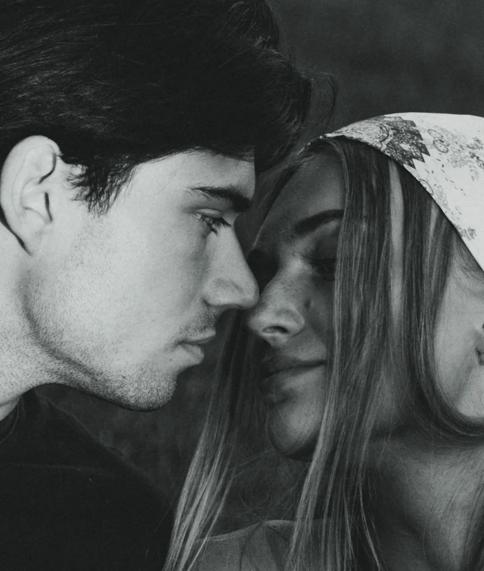 Black and white close-up of a man and woman with their foreheads touching, with their eyes closed.