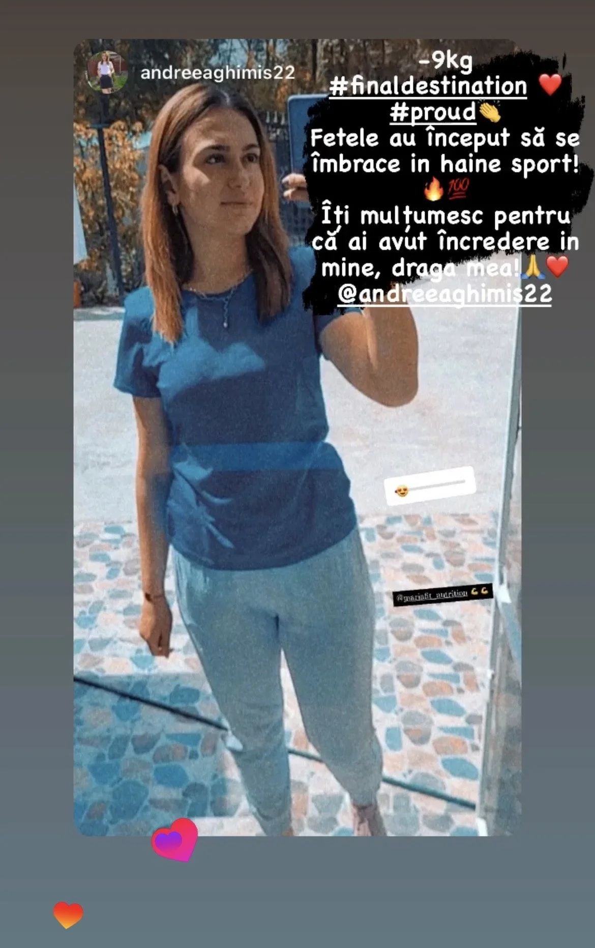 A woman takes a selfie outdoors, wearing a blue shirt and light gray pants, with trees and a paved surface in the background and various Russian text overlays with hashtags and emojis.