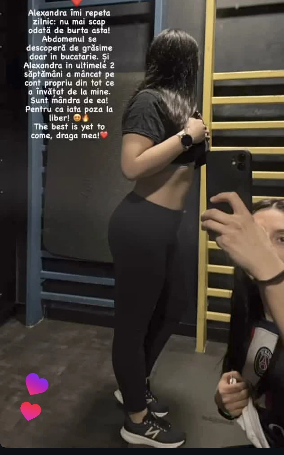 A woman taking a mirror selfie in a gym, wearing black leggings, a black crop top, and black running shoes. Text in Romanian and English is overlaid on the image, along with colorful heart emojis.