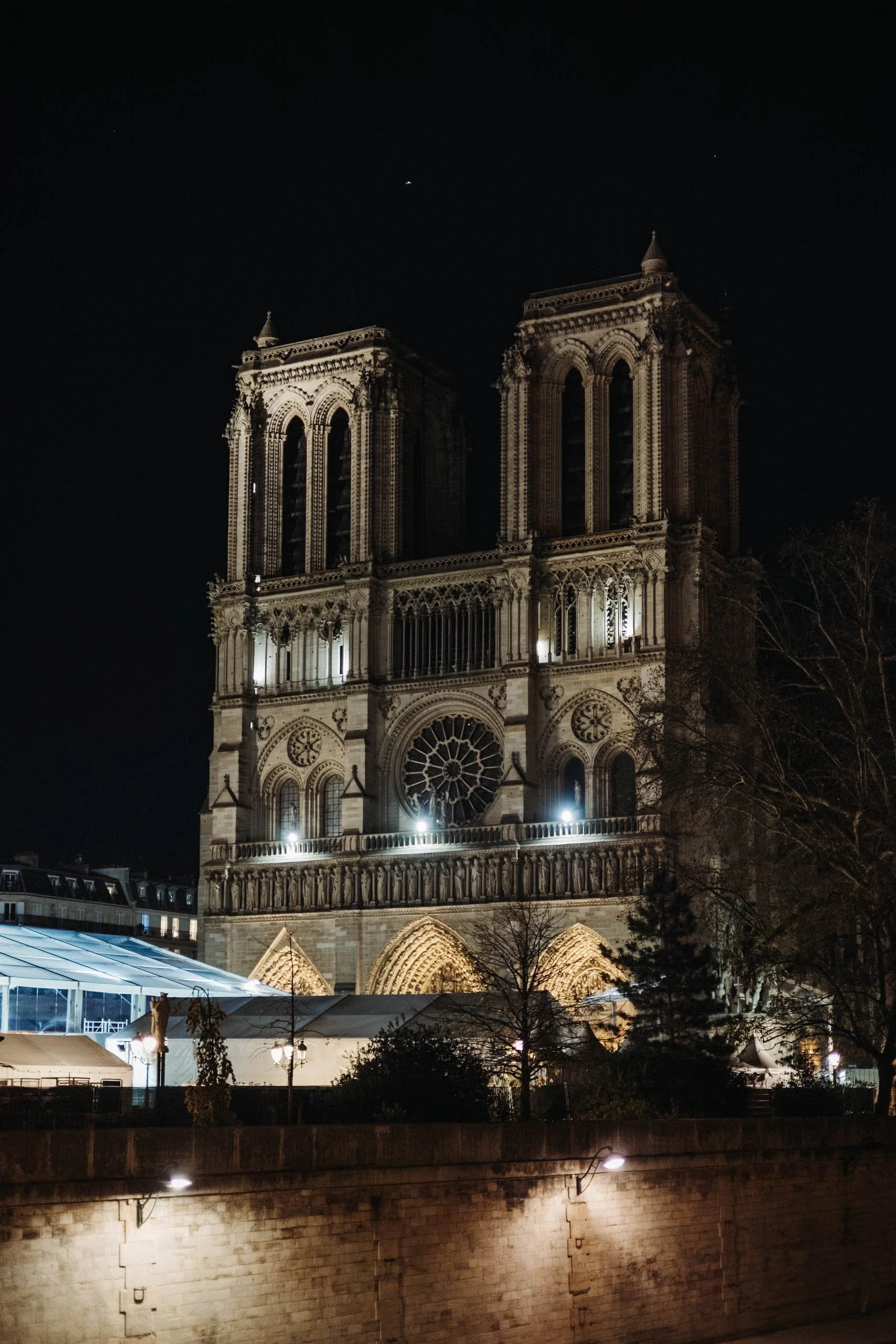 Night view of Notre-Dame Cathedral in Paris illuminated with exterior lighting.