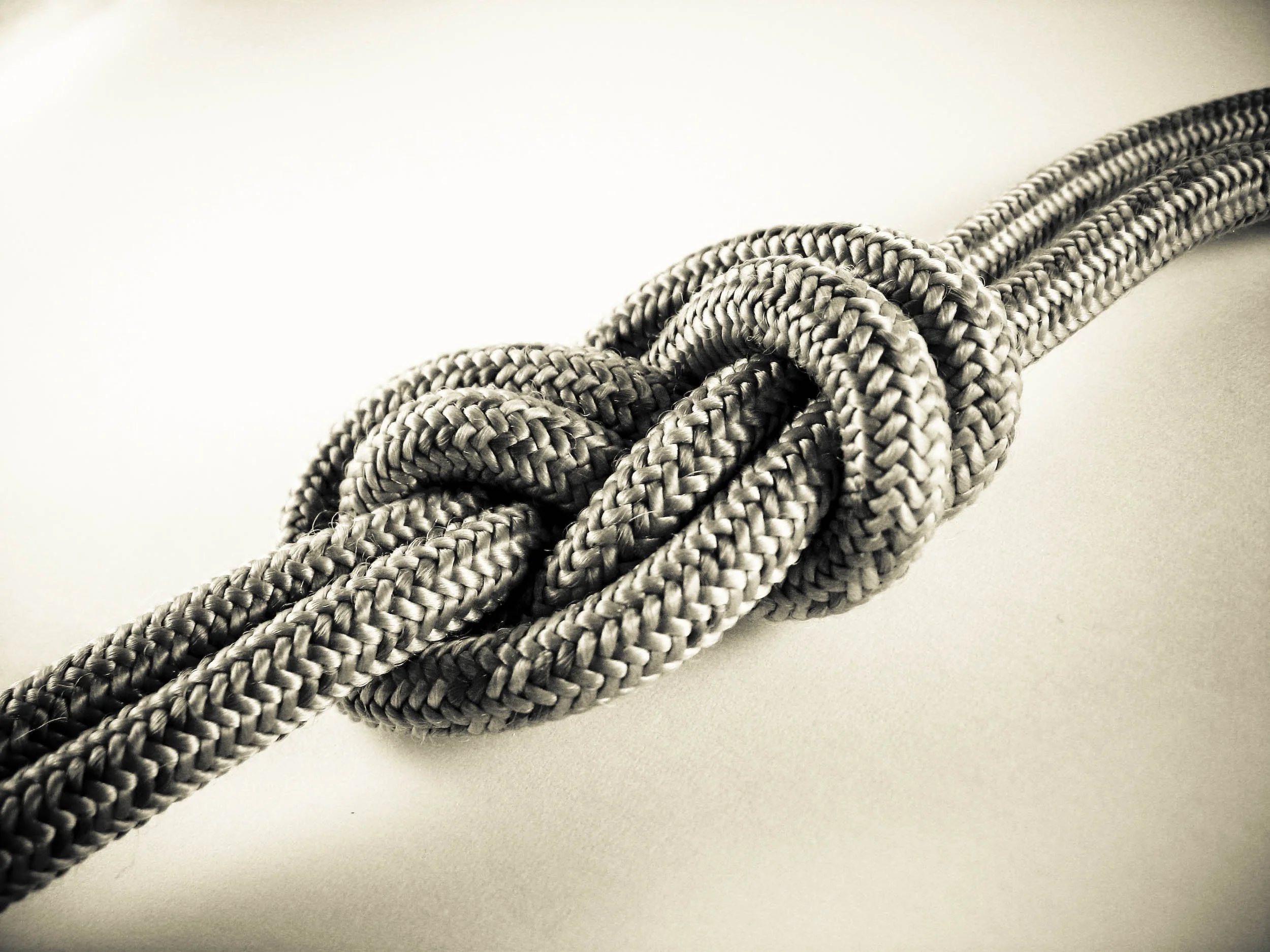 A tightly knotted loop of thick, braided gray rope on a plain background.