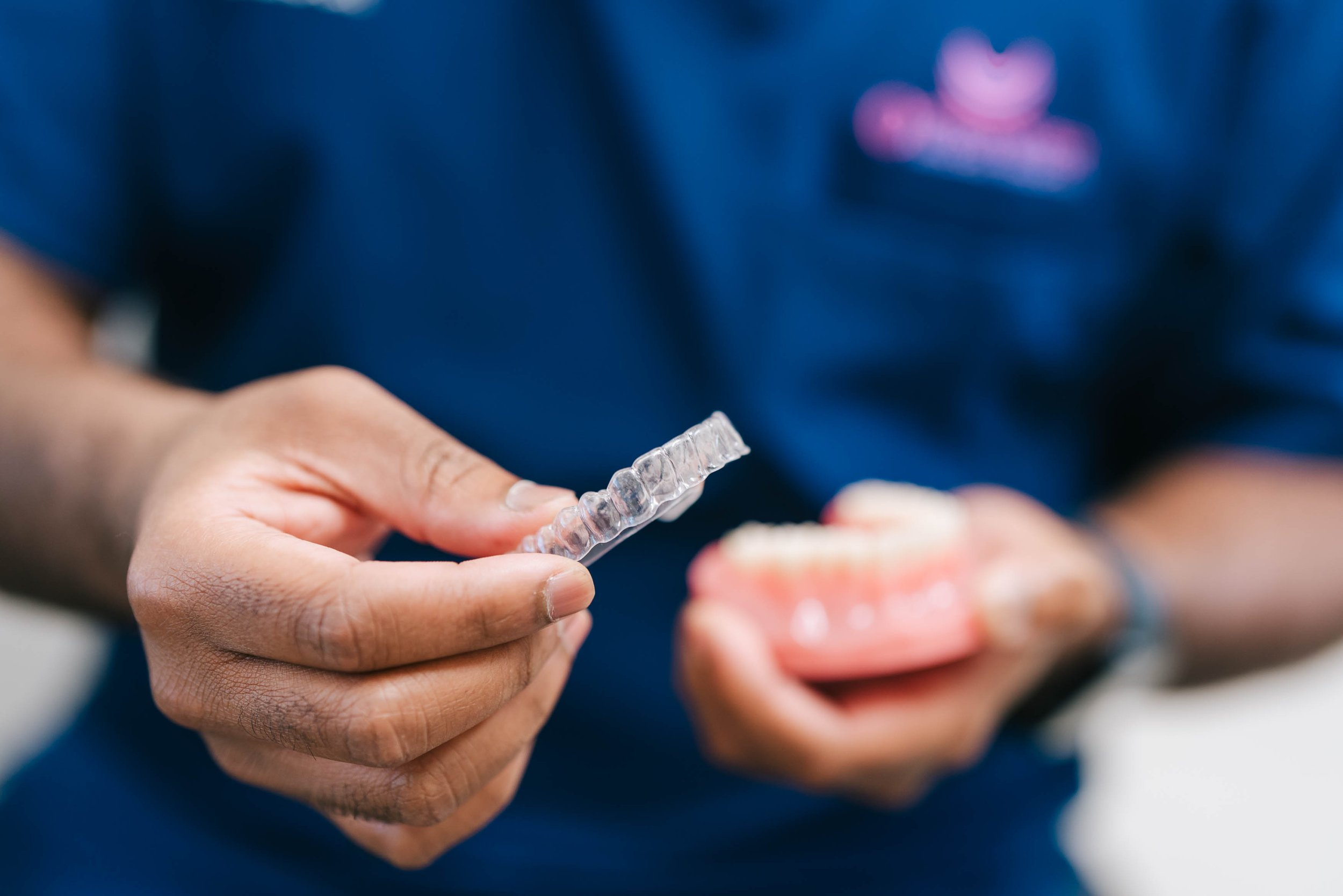 Person holding a clear aligner or dental tray in their hand.