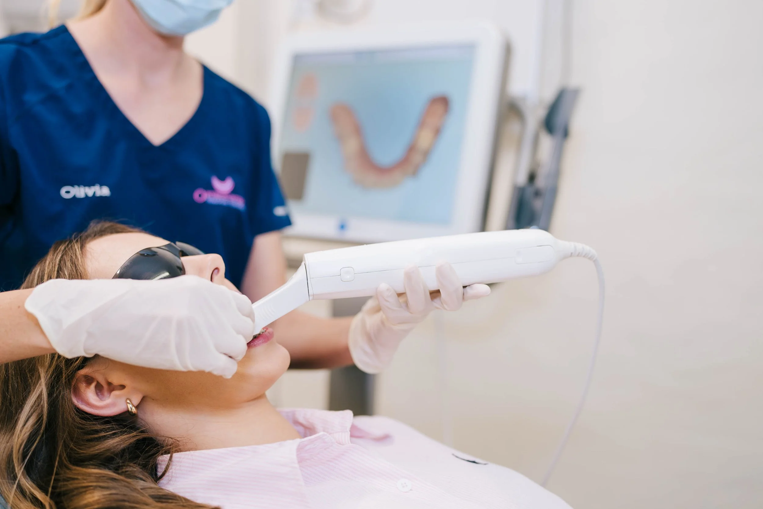 A dental assistant, is holding a dental scanning device
