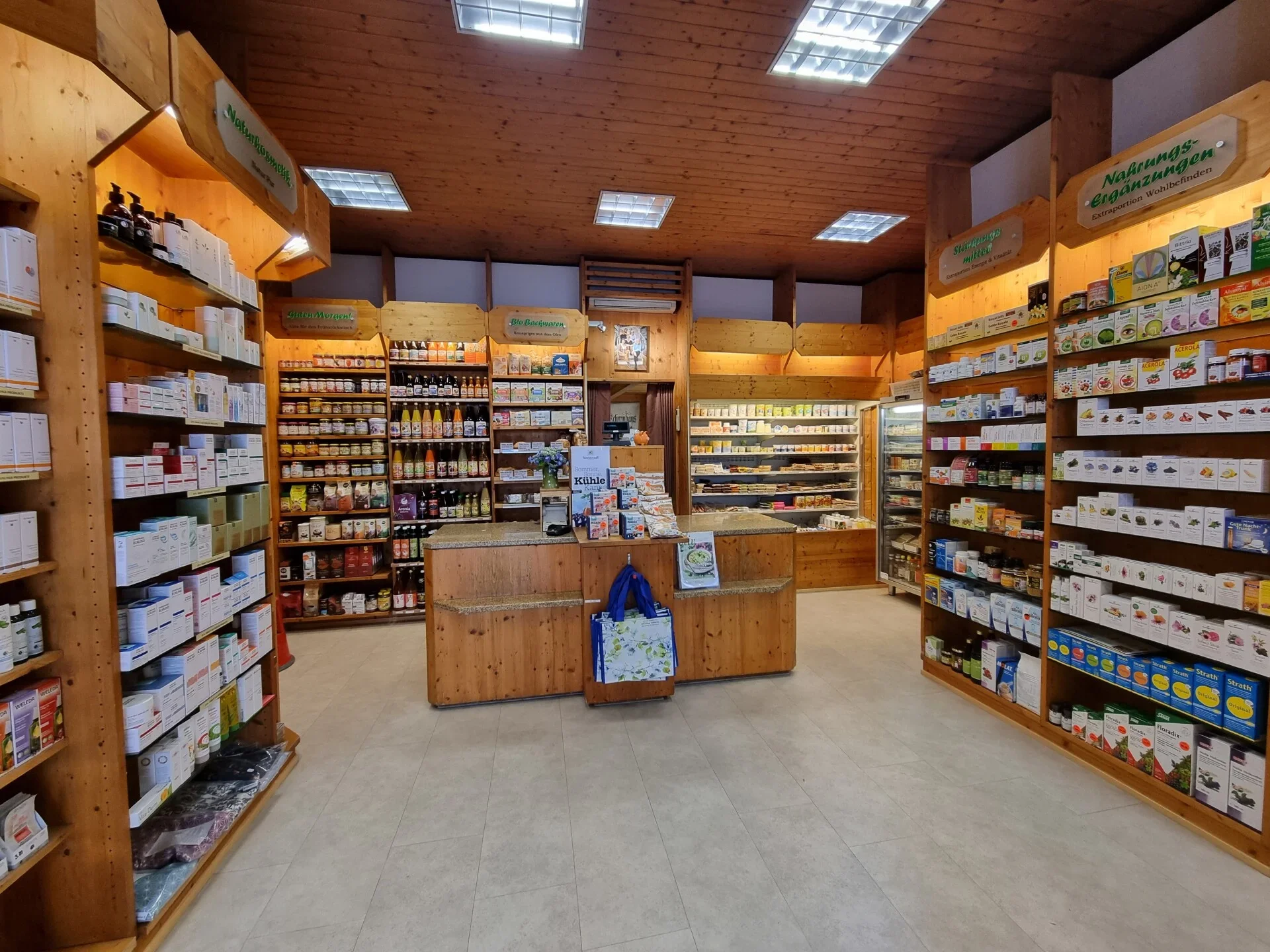 Inneneinrichtung eines Bioladens mit Holzregalen, die verschiedene Bio-Produkte und Nahrungsergänzungsmittel enthalten.