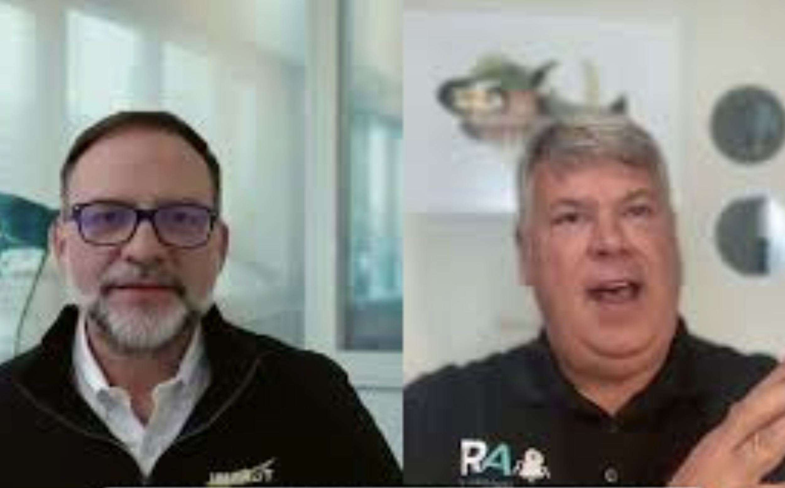 Side-by-side video call of two men; the man on the left has glasses, a white shirt, and a beard, while the man on the right has light-colored hair and is speaking, wearing a black polo shirt with logos.