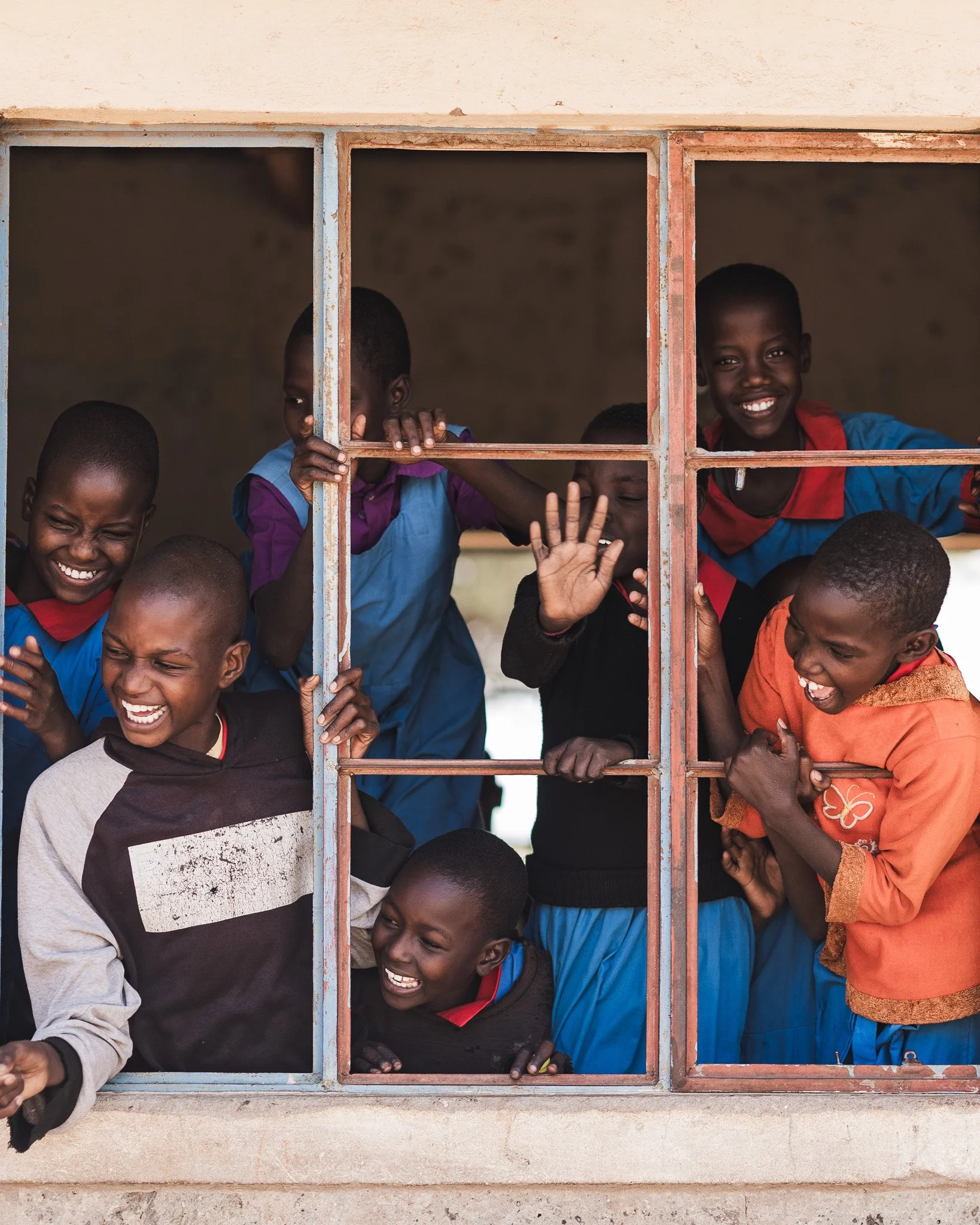 A group of students smiling behind a window
