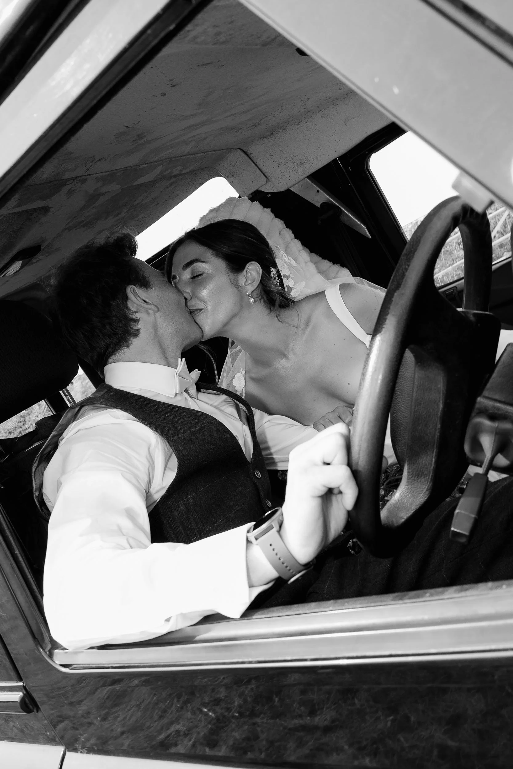 Bride and groom kissing in car candid wedding moment documentary style
