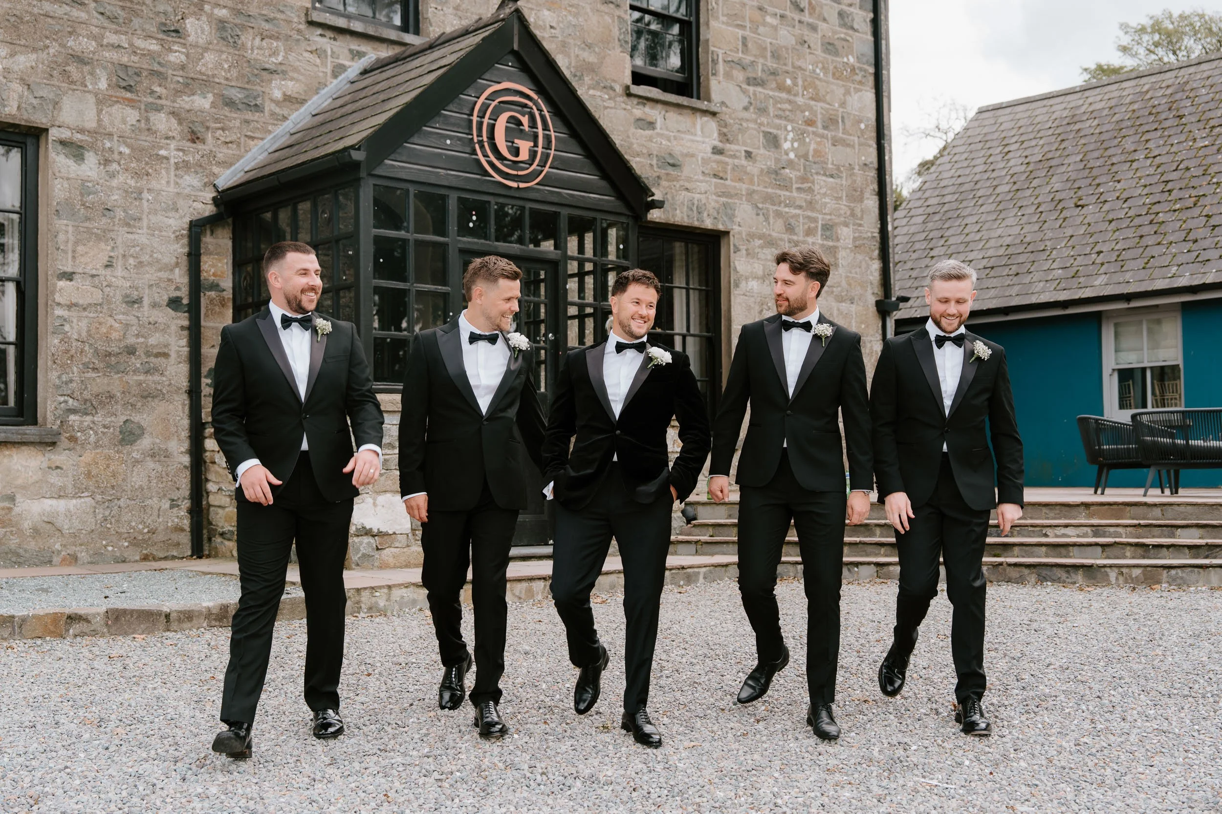 Unposed wedding photography groomsmen laughing coastal setting