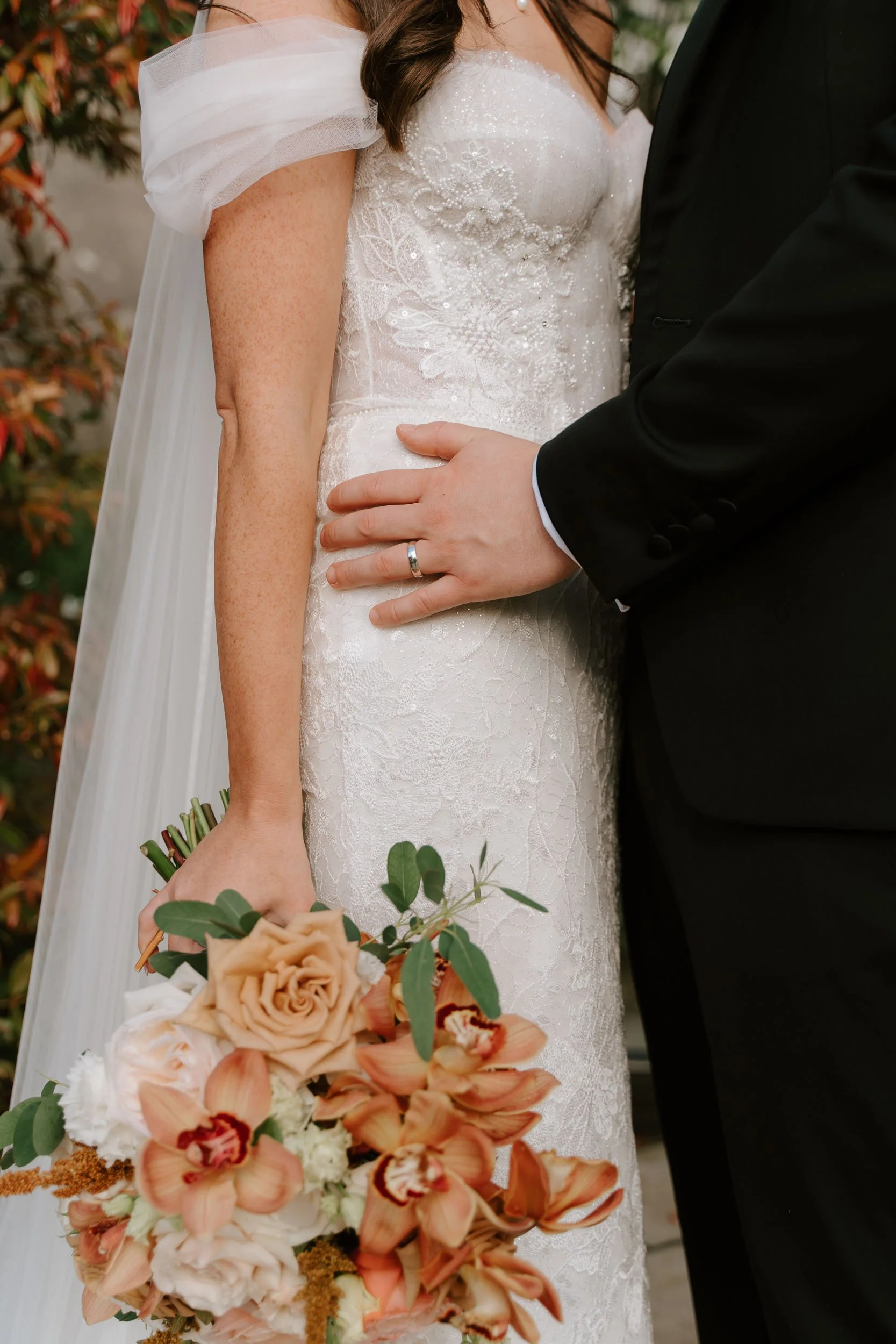 Bride and groom detail hands on dress bouquet close up