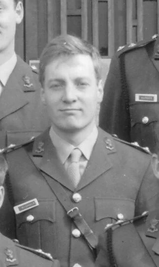 Black and white photo of Ross Nichols as a young man in military uniform with medals, standing outdoors with others in similar uniforms.