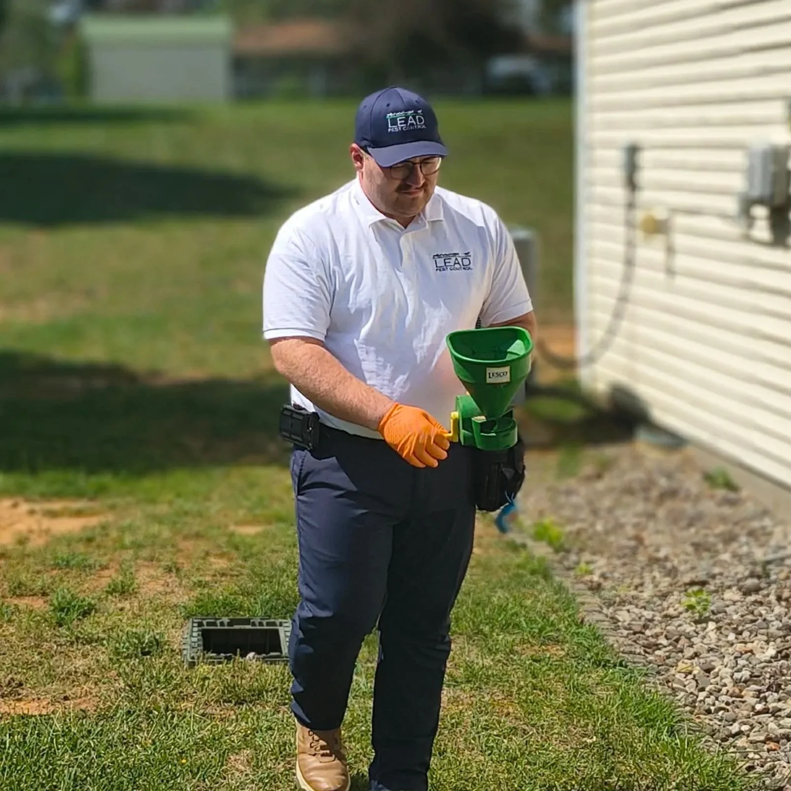 Pest control technician applying granular treatment around home foundation in Elizabethtown KY